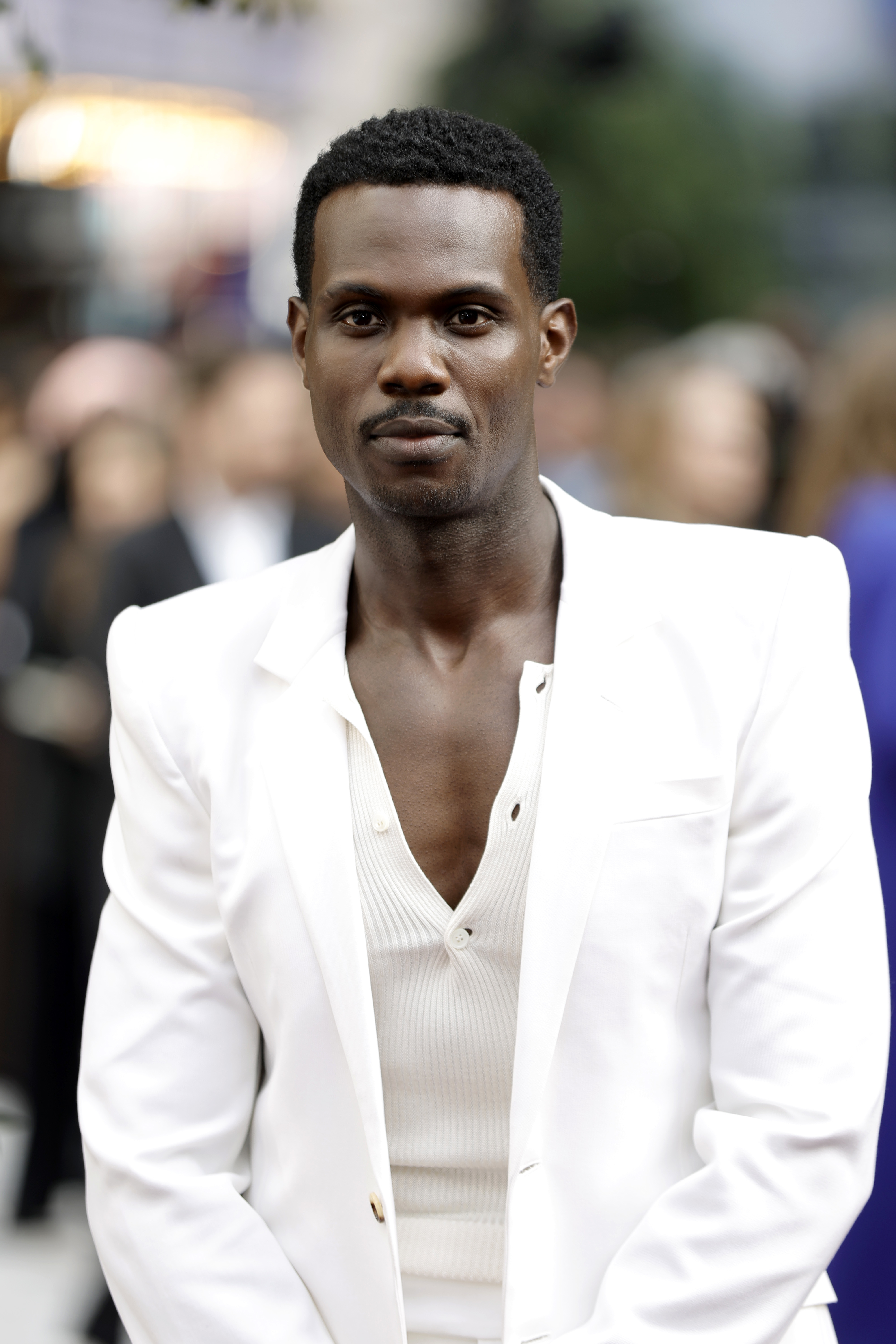 Victor Alli in a white blazer and ribbed shirt at a red carpet event