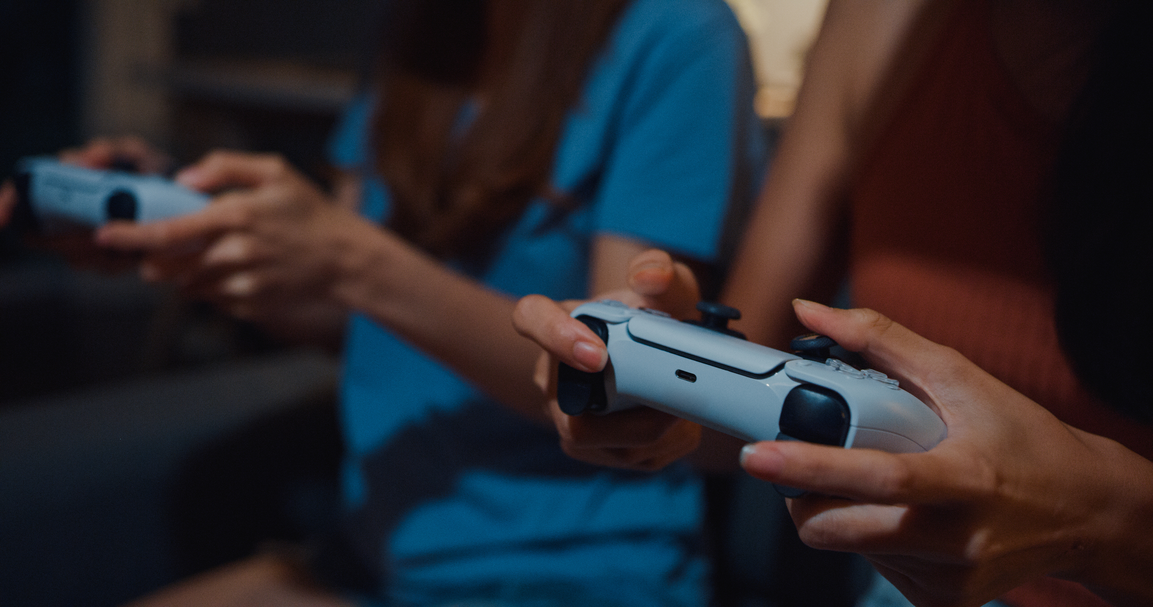 People playing a video game, focusing on their hands holding game controllers. Faces are not visible
