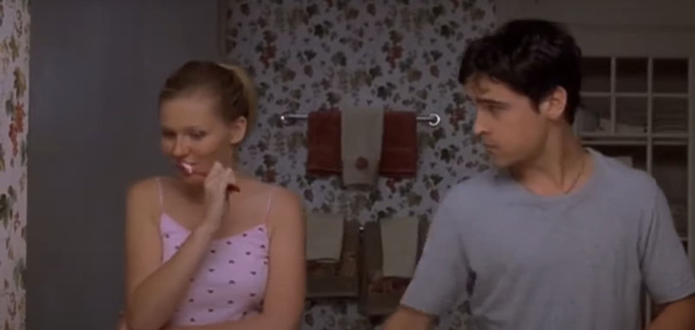 Margot Robbie, in a polka dot top, and a man brush teeth in a floral wallpapered bathroom from the film &quot;About Time&quot;