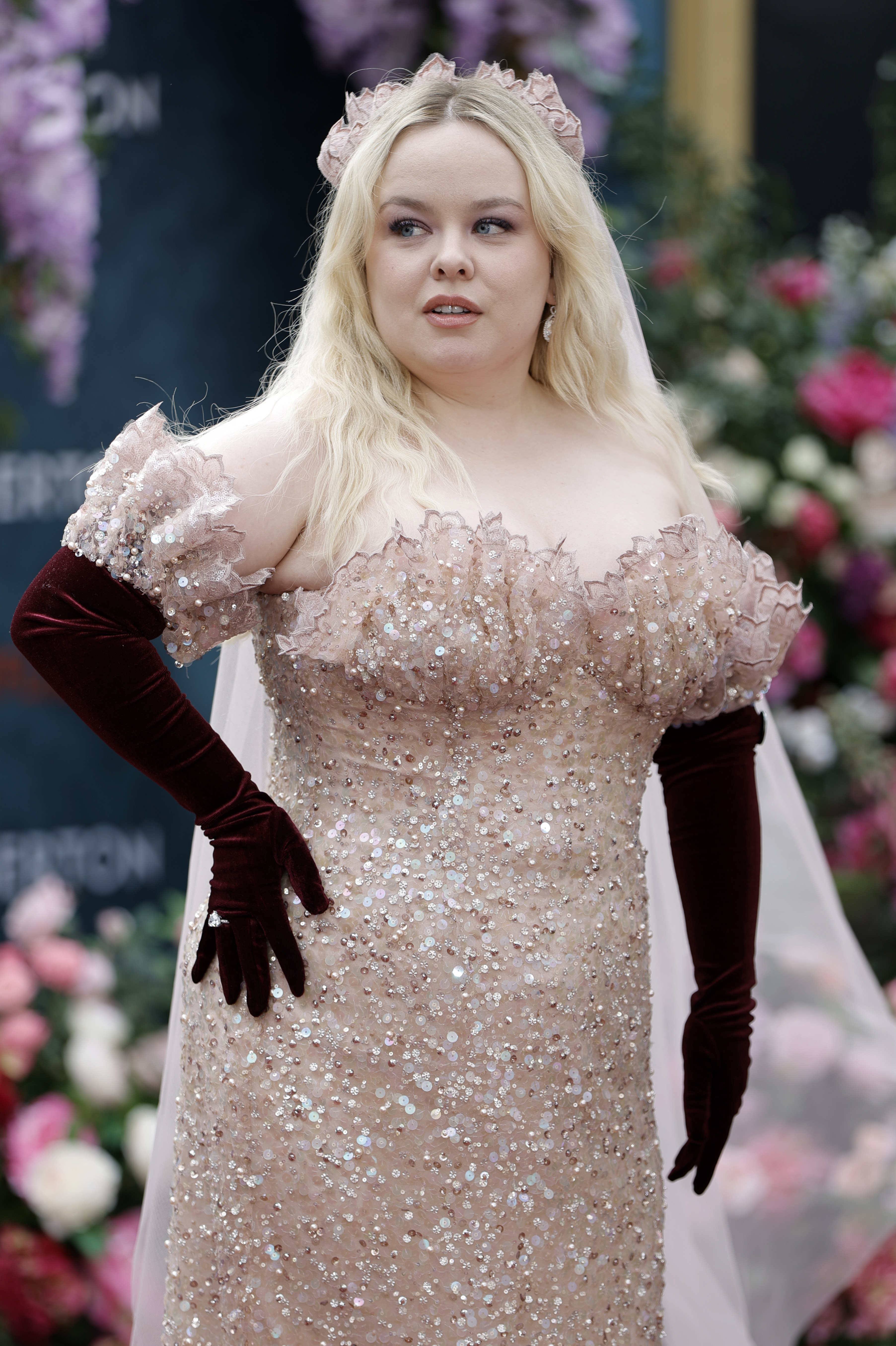 Nicola Coughlan poses on the red carpet in a shimmering, off-the-shoulder gown with long gloves and a matching hair accessory