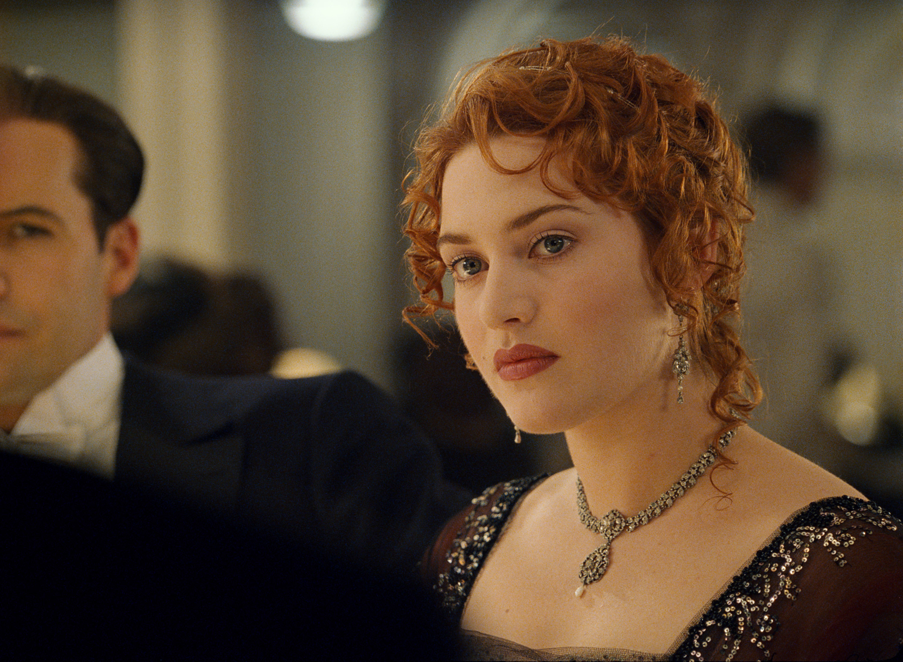 Kate Winslet and a man in formal attire, with Kate wearing an elegant, bejeweled gown and intricate accessories