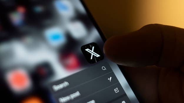 Smartphone screen showing the Twitter app icon, now rebranded as X, with a finger about to tap it