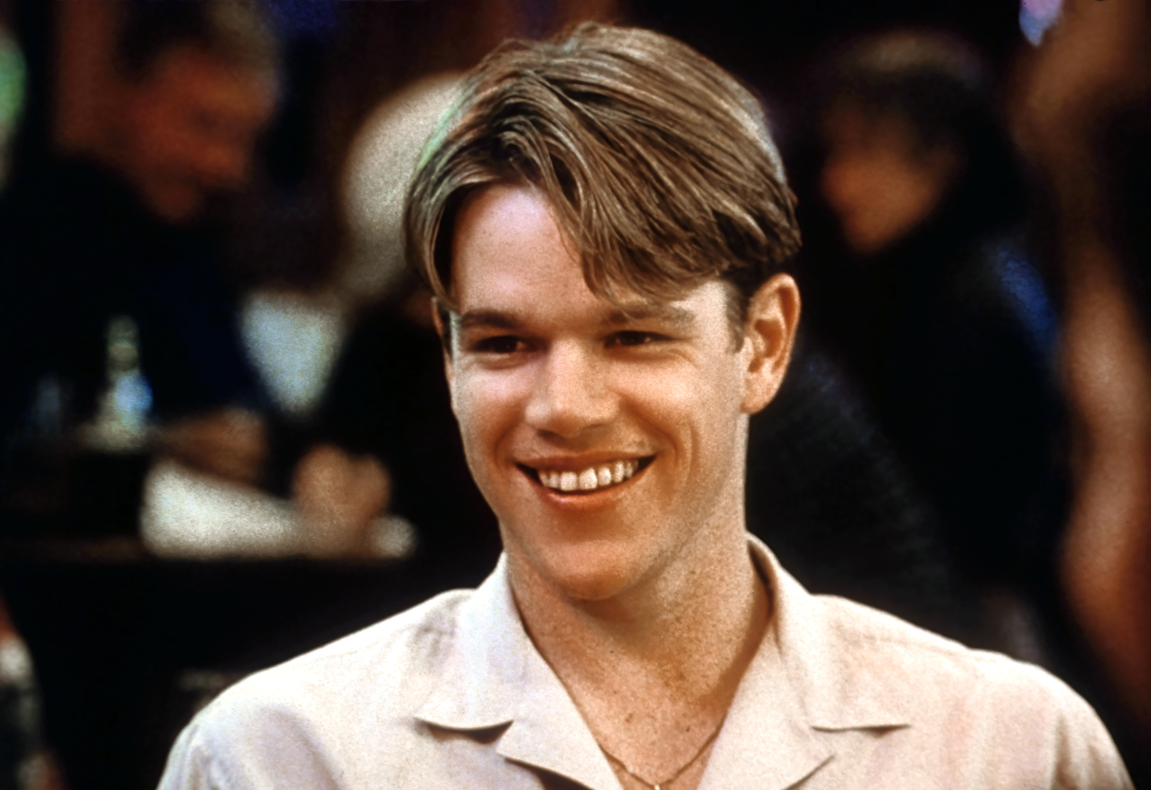Matt Damon smiling in a close-up shot, wearing a casual button-up shirt