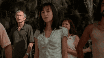 Several Lost characters, including Jin and Sun, stand together, looking around and appearing concerned.