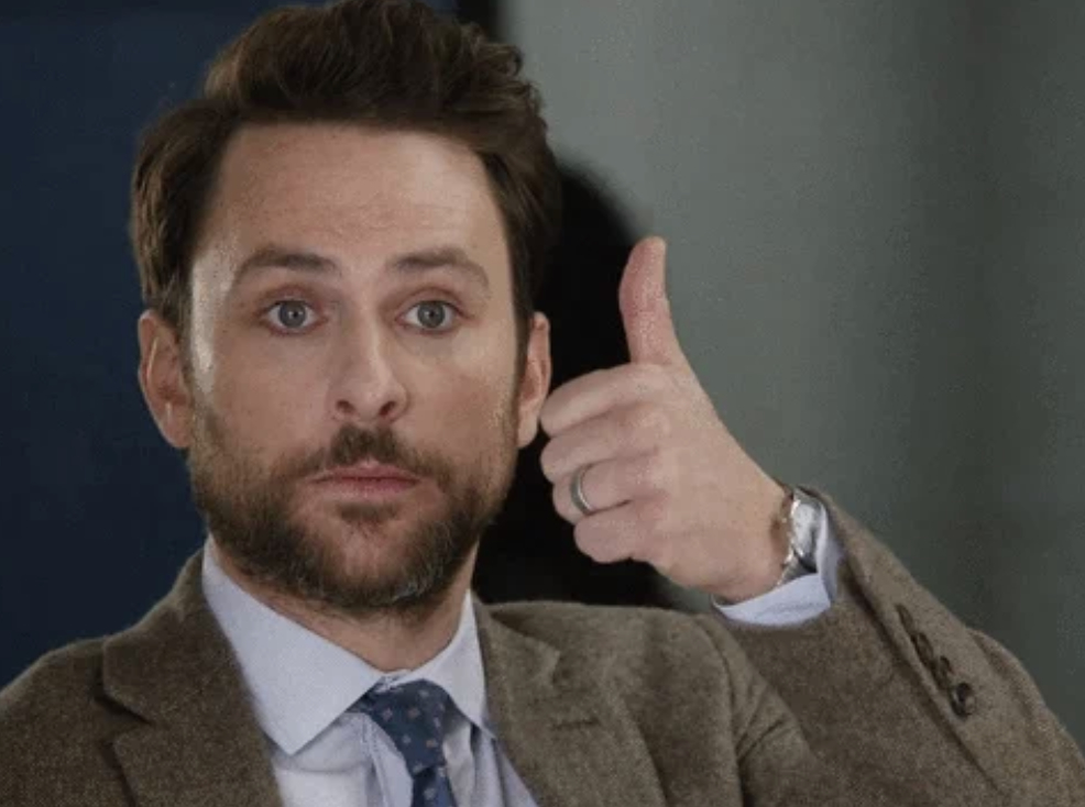 I don't know who is in this image. A man with a beard and mustache in a suit and tie gives a thumbs-up gesture