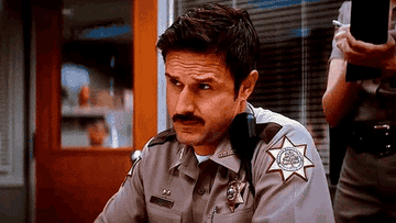 Dewey Riley, in his police uniform, nods his head.