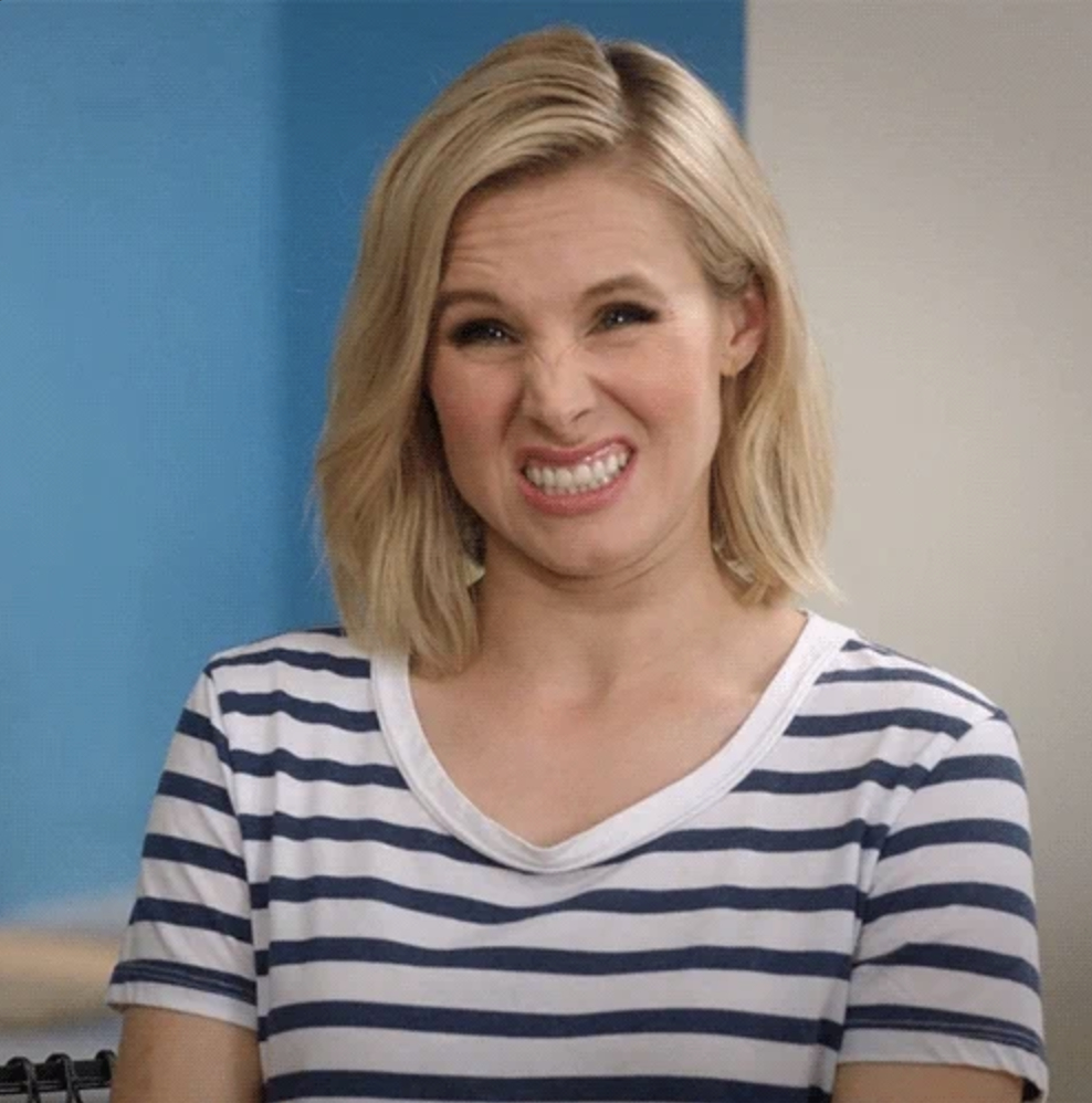 Kristen Bell making a humorous, scrunched face. She wears a striped shirt and has shoulder-length hair