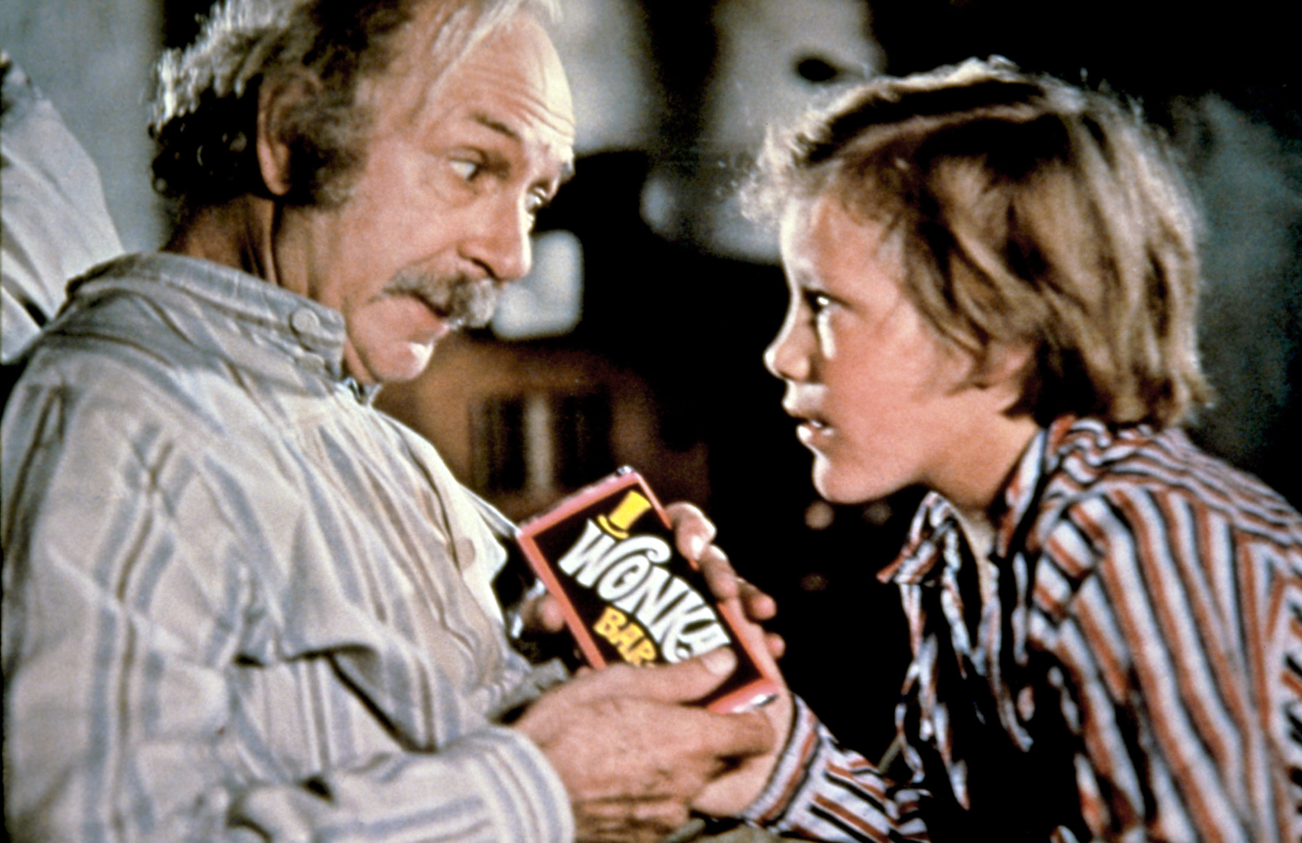 Jack Albertson and Peter Ostrum, dressed in pajamas, holding a Wonka Bar in a scene from "Willy Wonka & the Chocolate Factory."