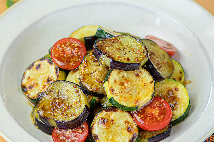 焼きナス、ズッキーニ、トマトのサラダが皿に盛り付けられています。粒マスタードのソースがかかっています。