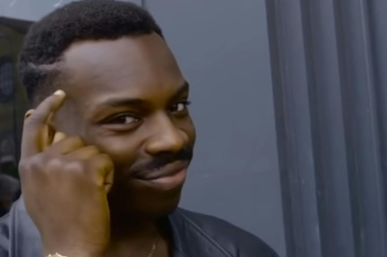 Man in a black leather jacket tapping his temple, implying a smart idea