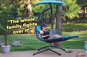 A person is lounging in a comfortable outdoor chair with a canopy, working on a laptop. Text on the image reads, "The whole family fights over it!"