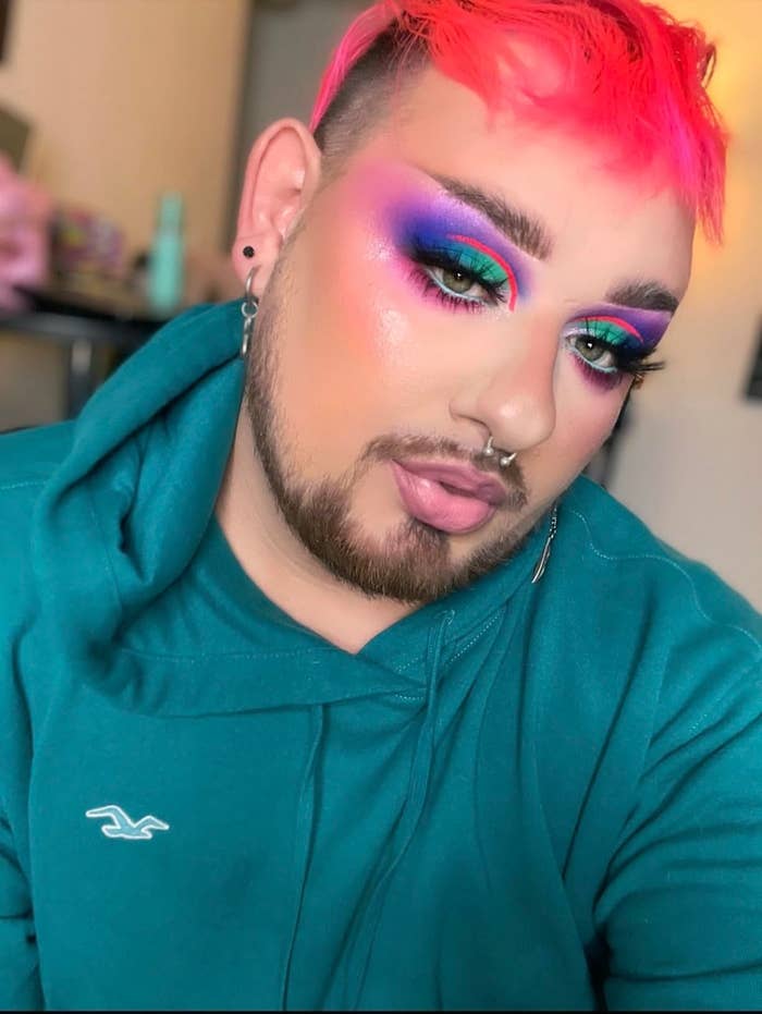 reviewer with vibrant makeup, including bold eyeshadow and contouring, wearing a hoodie