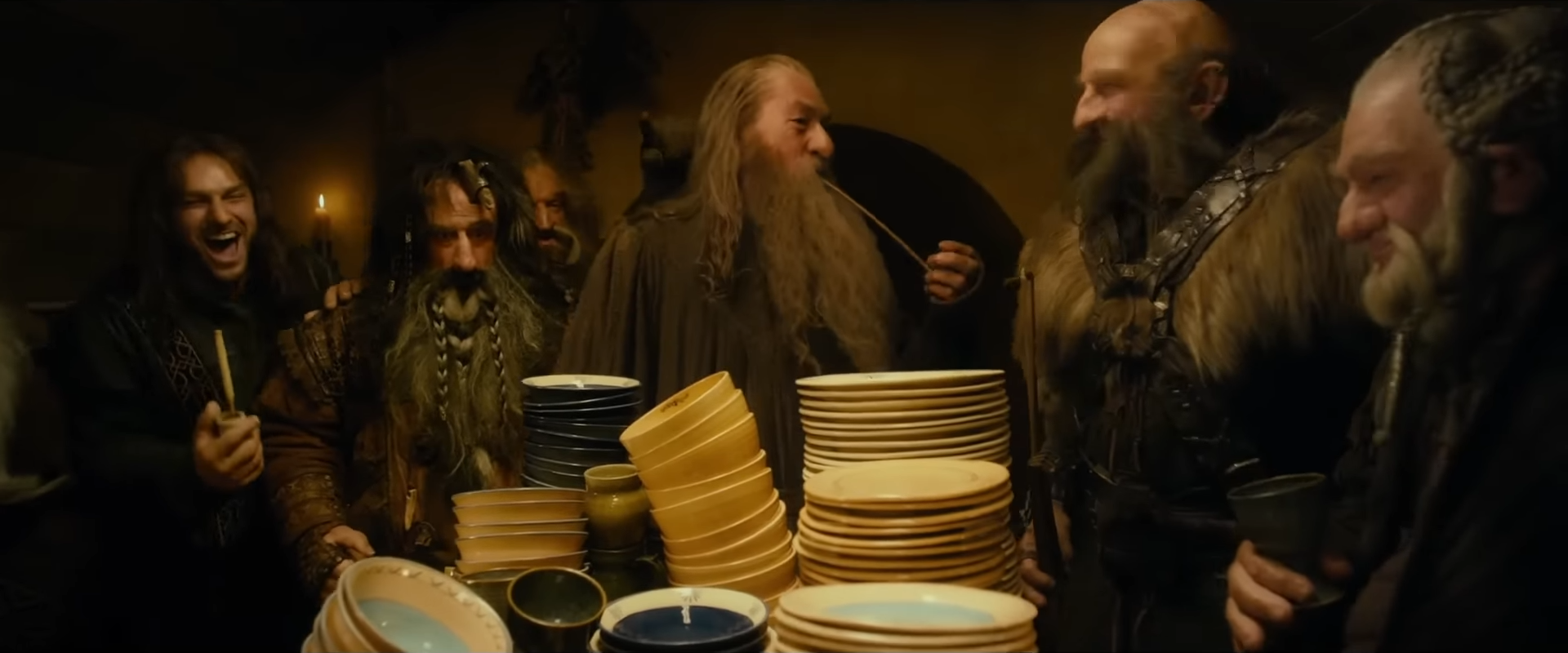 Richard Armitage, Graham McTavish, John Callen, and other actors dressed as dwarves laughing around a table piled with dishes in a scene from &quot;The Hobbit.&quot;
