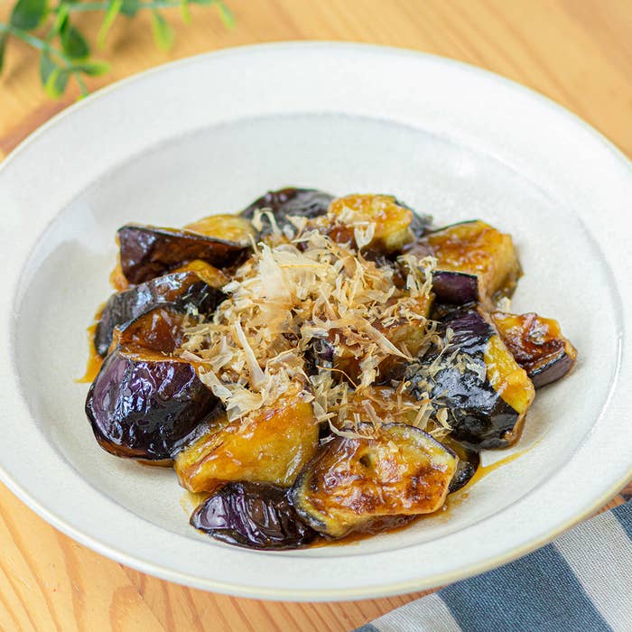 白い皿に盛り付けられたなすの炒め物。皿にはかつお節が飾られています。