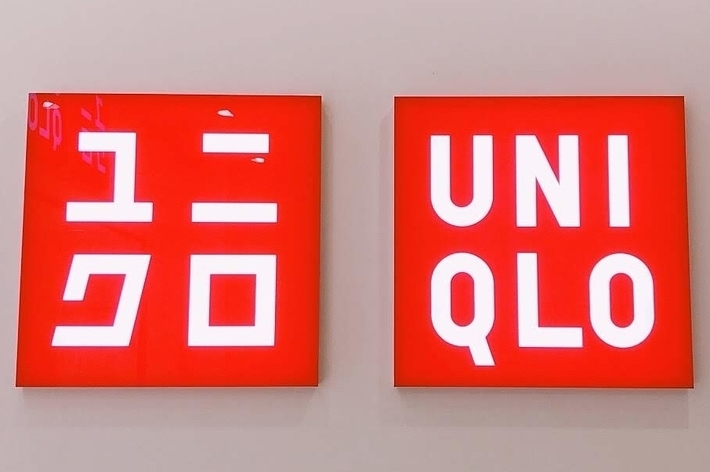 Two red signs with white text: the left sign has Japanese characters, the right sign reads &ldquo;Uniqlo.&quot;