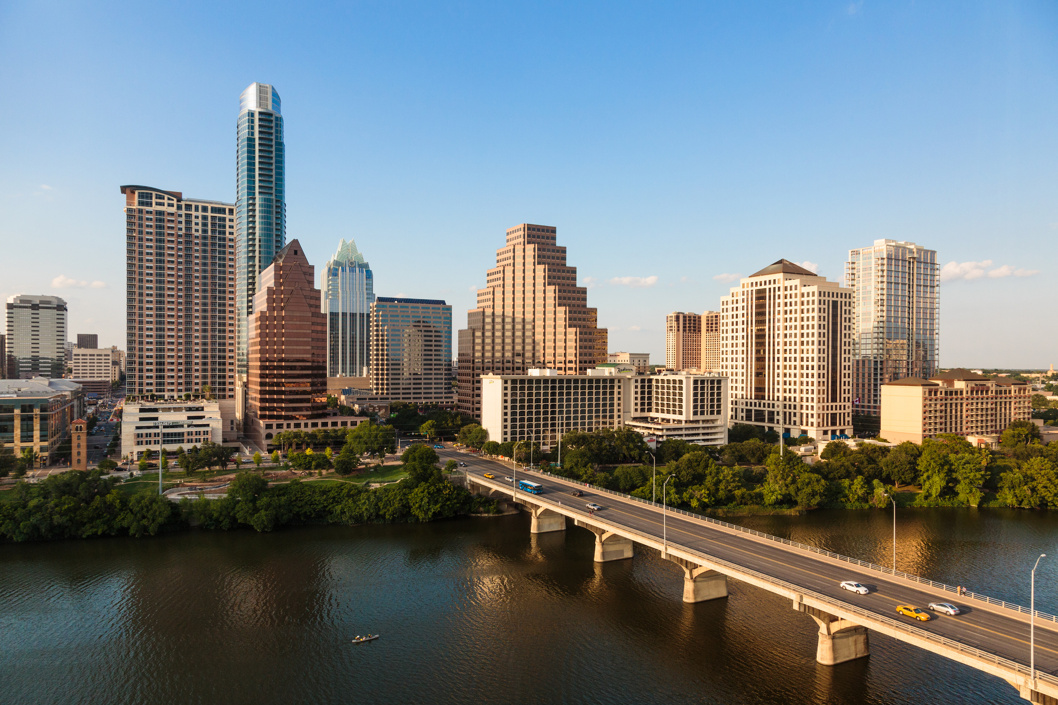 Austin city skyline featuring tall buildings and a bridge over the water, highlighting notable architecture and a mix of modern and classic designs