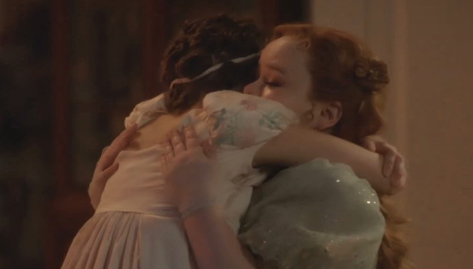 Daphne Bridgerton abraza a su hermana Eloise Bridgerton en una escena de la serie "Bridgerton". Daphne lleva un vestido de época con detalles florales