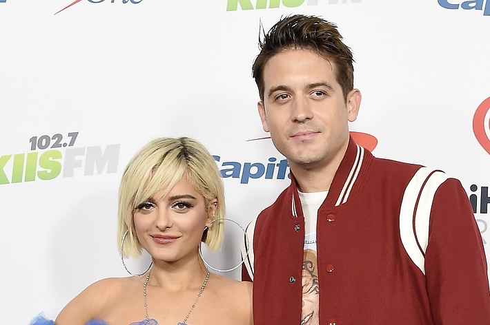 Bebe Rexha in a strapless dress and G-Eazy in a red varsity jacket pose together at a music event