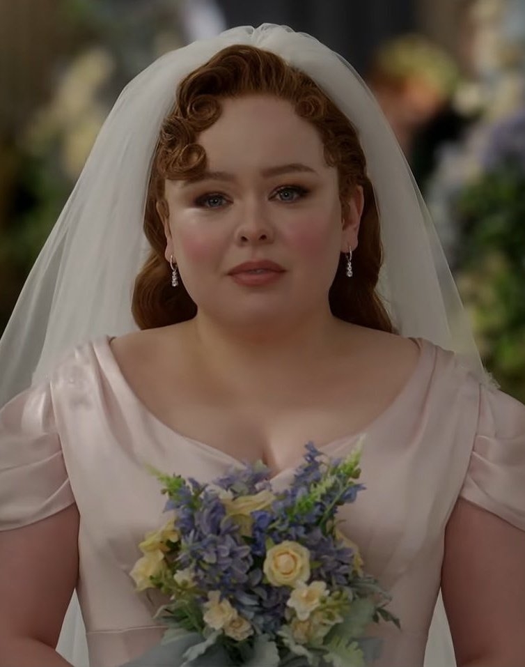 Nicola Coughlan vestida de novia, sosteniendo un ramo de flores en escena de TV