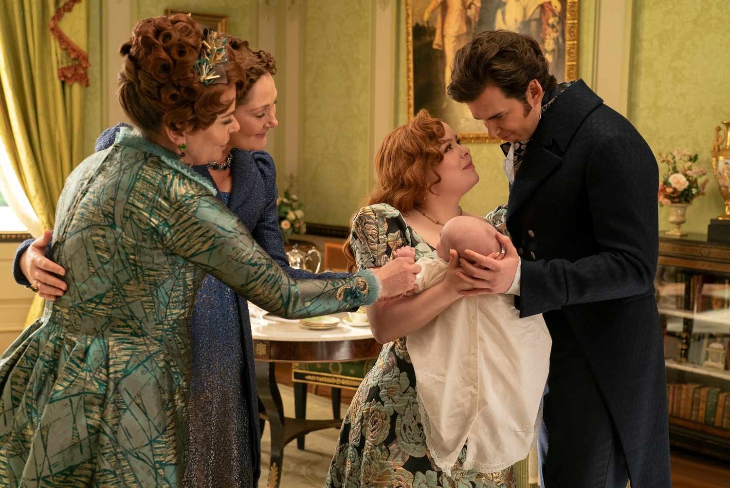 Adjoa Andoh, Ruth Gemmell, Nicola Coughlan y Luke Thompson participan en una escena de época; Nicola sostiene un bebé mientras los otros actores la rodean