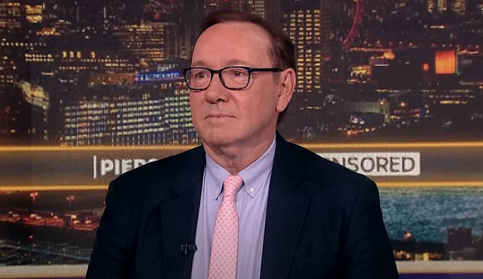 Kevin Spacey in a dark suit, light tie, and glasses on a news set with city lights in the background. &quot;Piers Morgan Uncensored&quot; on screen