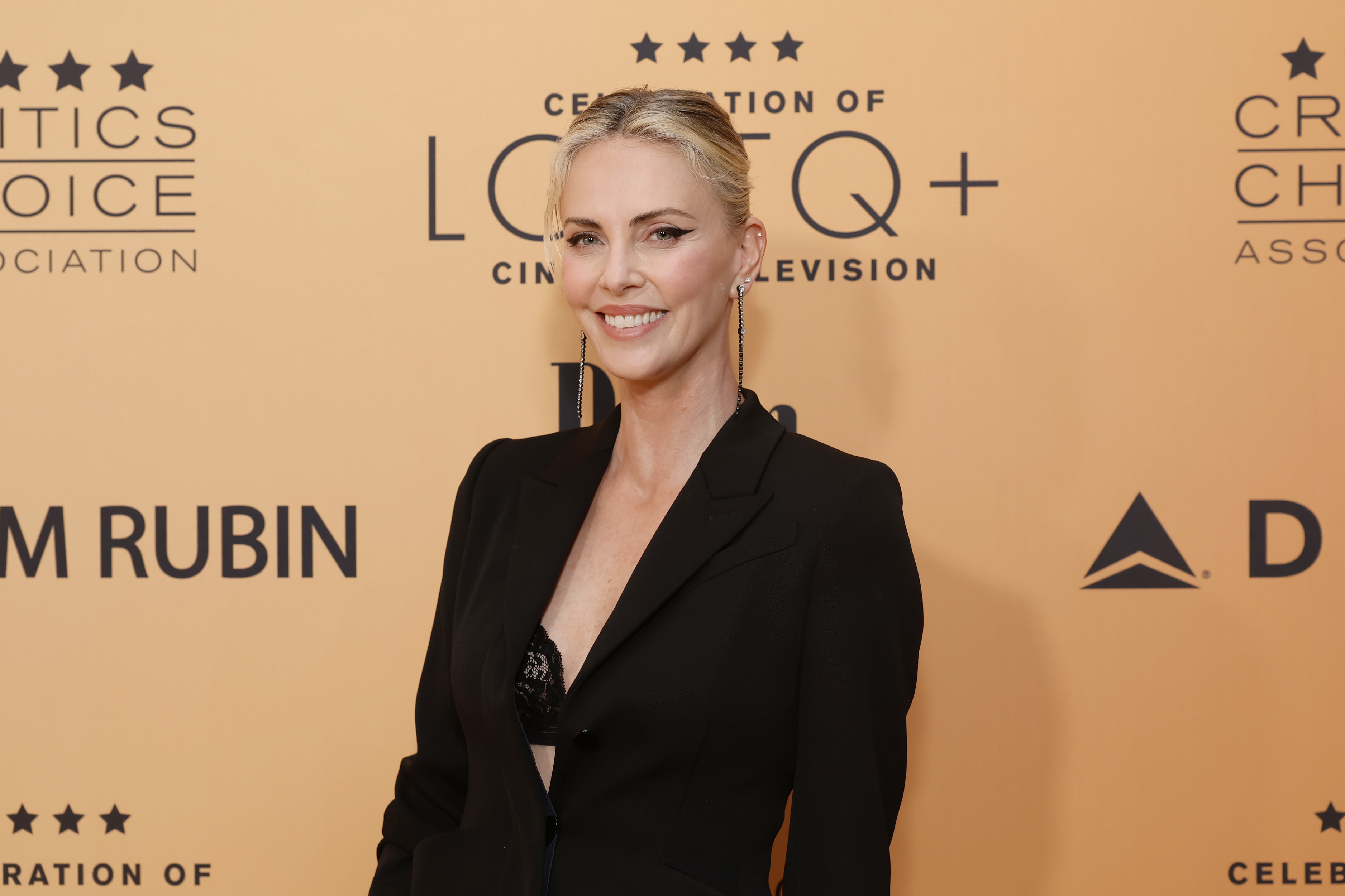 Charlize Theron at a Critics Choice Association event, wearing a stylish black suit jacket with a deep neckline