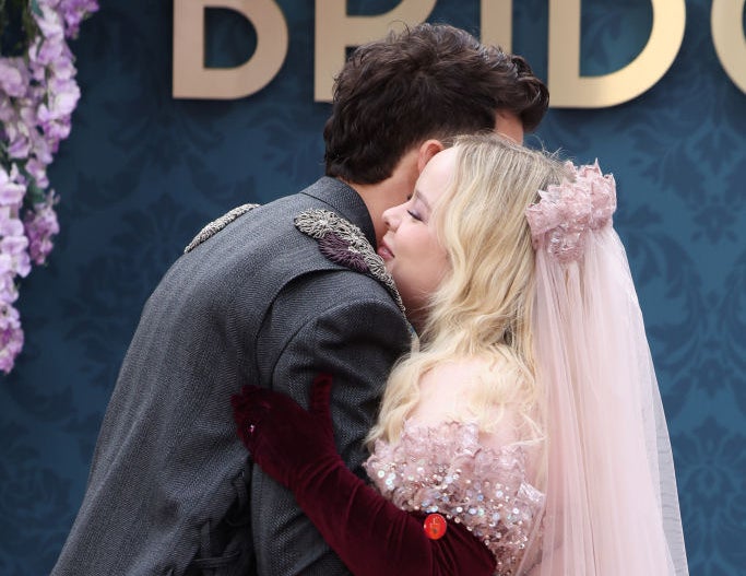 Nicola Coughlan in a sparkling gown and veil hugs Luke Newton, who is wearing a formal suit, at a "Bridgerton" event