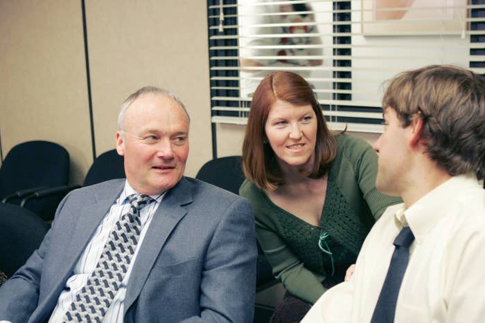 Creed Bratton, Kate Flannery, and John Krasinski are sitting and conversing in an office setting