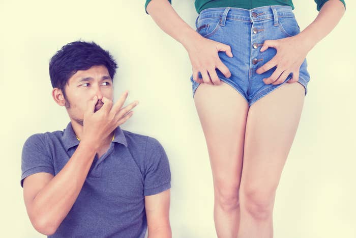 A person holds their nose while looking at another person&#x27;s shorts. The person with shorts stands with their hands on their thighs