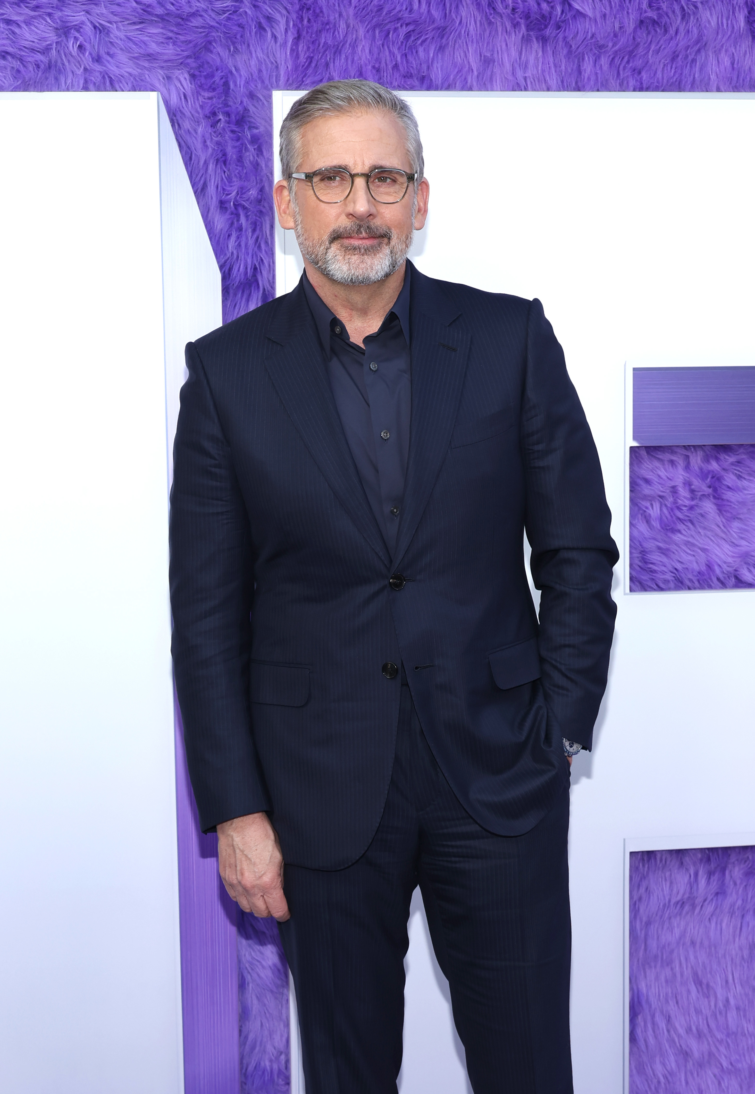 Steve Carell in a pinstripe suit and glasses at an event