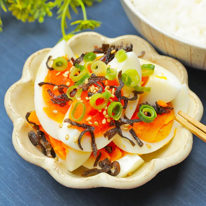 皿に盛り付けられたゆで卵の上に、海藻やネギがトッピングされている。