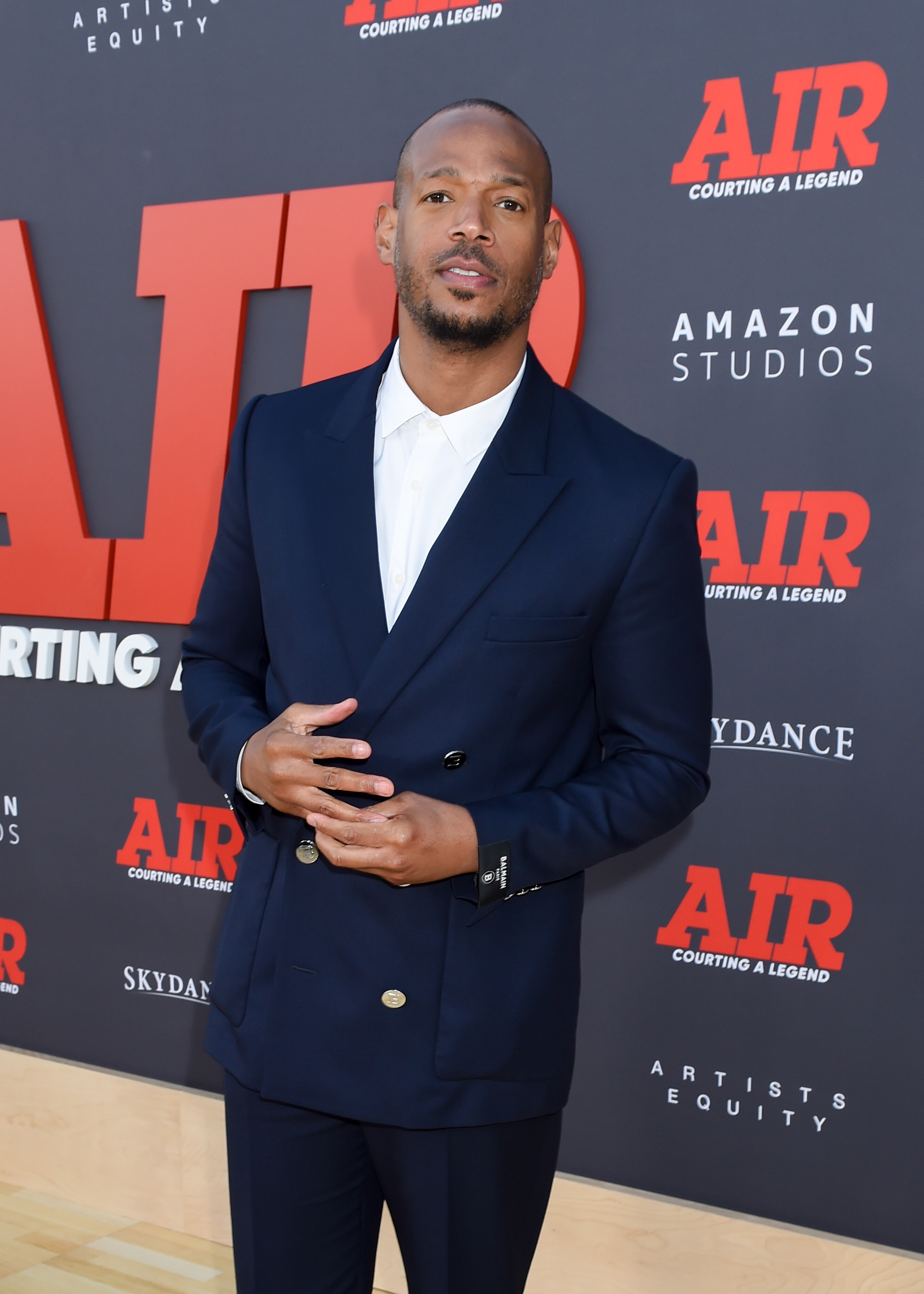Marlon Wayans stands on the red carpet for the "Air" premiere, wearing a navy double-breasted suit with a white shirt underneath