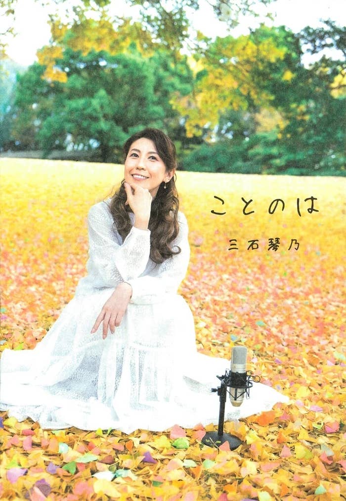 三石琴乃が秋の葉で覆われた野外で白いドレスを着て座っている。テキストには「ことのは 三石琴乃」と書かれている。