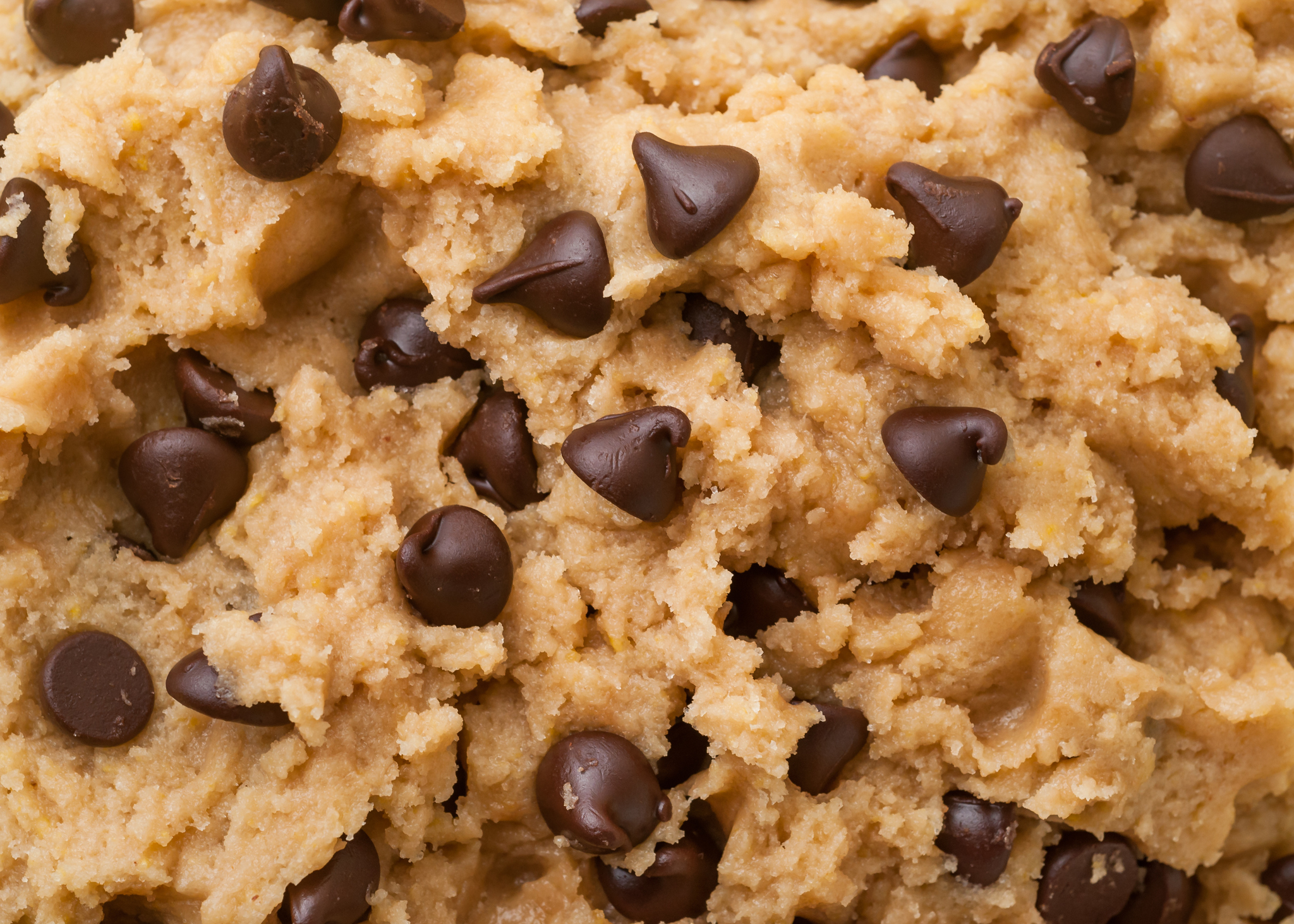 Close-up shot of chocolate chip cookie dough with numerous chocolate chips embedded in the mix