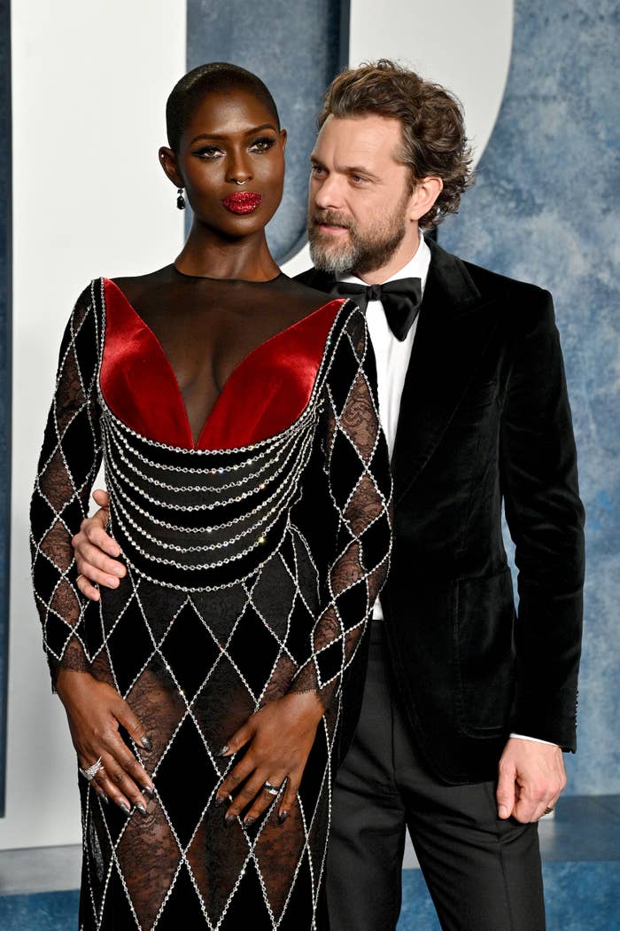 Jodie Turner-Smith in a geometric patterned dress with a deep V-neck and Joshua Jackson in a dark suit at a formal event
