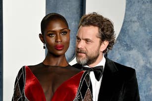 Jodie Turner-Smith in a geometric patterned dress with a deep V-neck and Joshua Jackson in a black suit at a formal event. They pose together closely