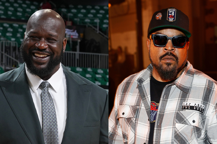 Shaquille O'Neal in a suit smiles, standing in an arena. Ice Cube in a plaid shirt and sunglasses, wearing a cap with logos, stands at the Big3 event