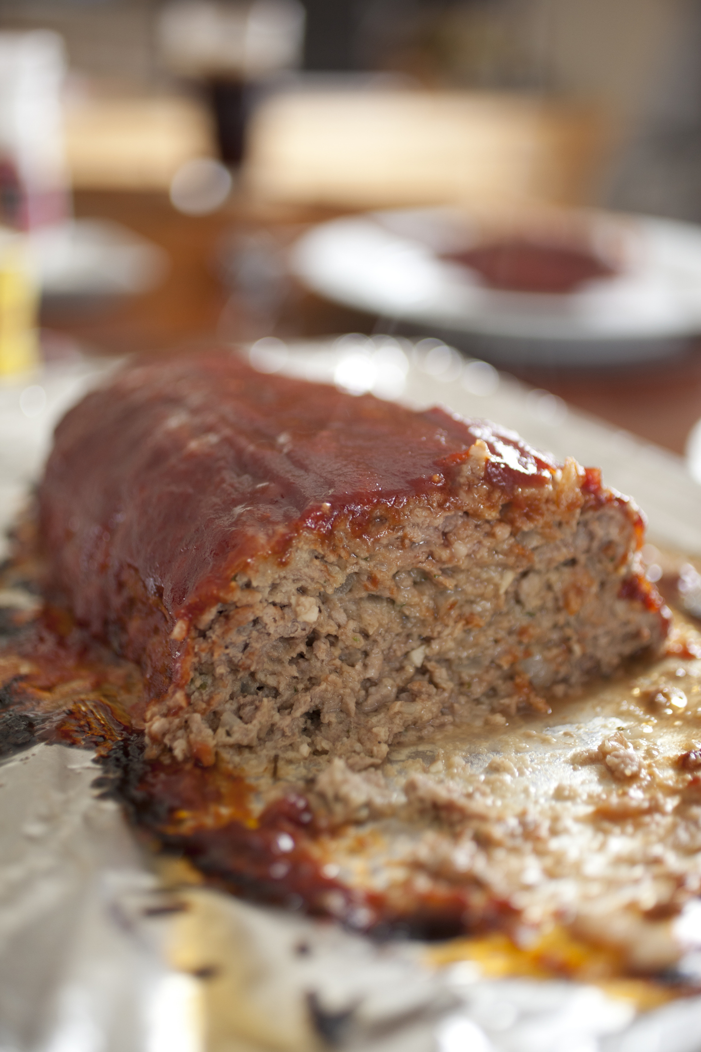 A baked meatloaf, partially sliced, placed on foil inside a kitchen
