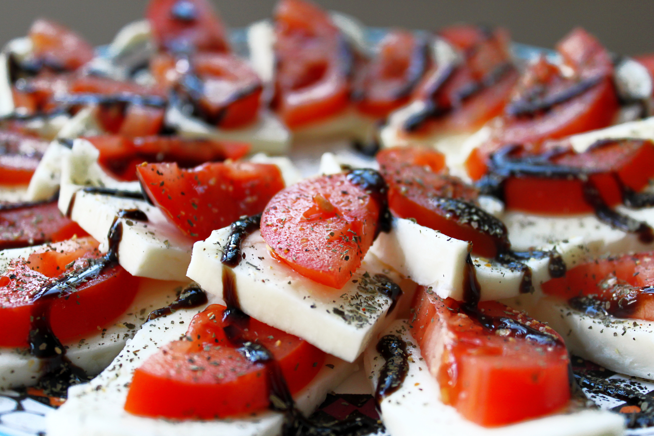 Close-up of a Caprese salad with sliced tomatoes, mozzarella cheese, and a drizzle of balsamic glaze