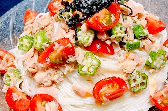 透明なガラス皿に盛り付けられた冷製パスタ。トッピングにはトマト、オクラ、ツナがのっています。