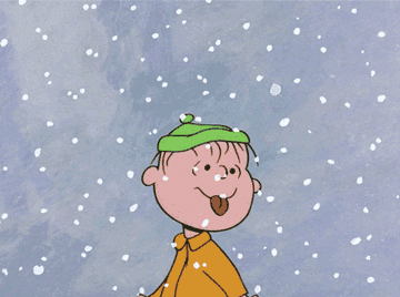 Linus from &quot;A Charlie Brown Christmas&quot; wearing a green hat and yellow coat, sticks out his tongue to catch falling snowflakes