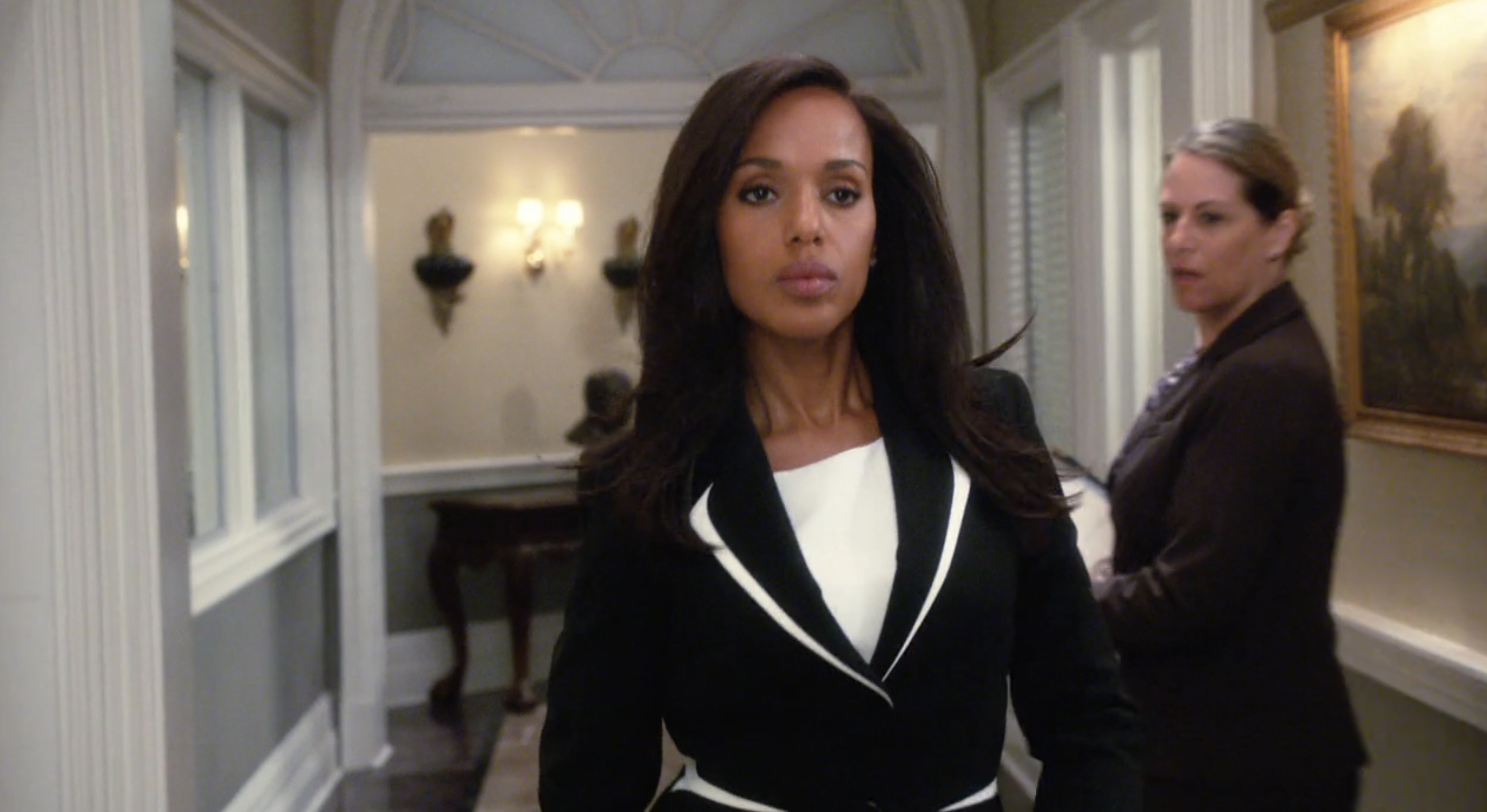 Kerry Washington walks confidently in a tailored blazer down a hallway, with a serious expression