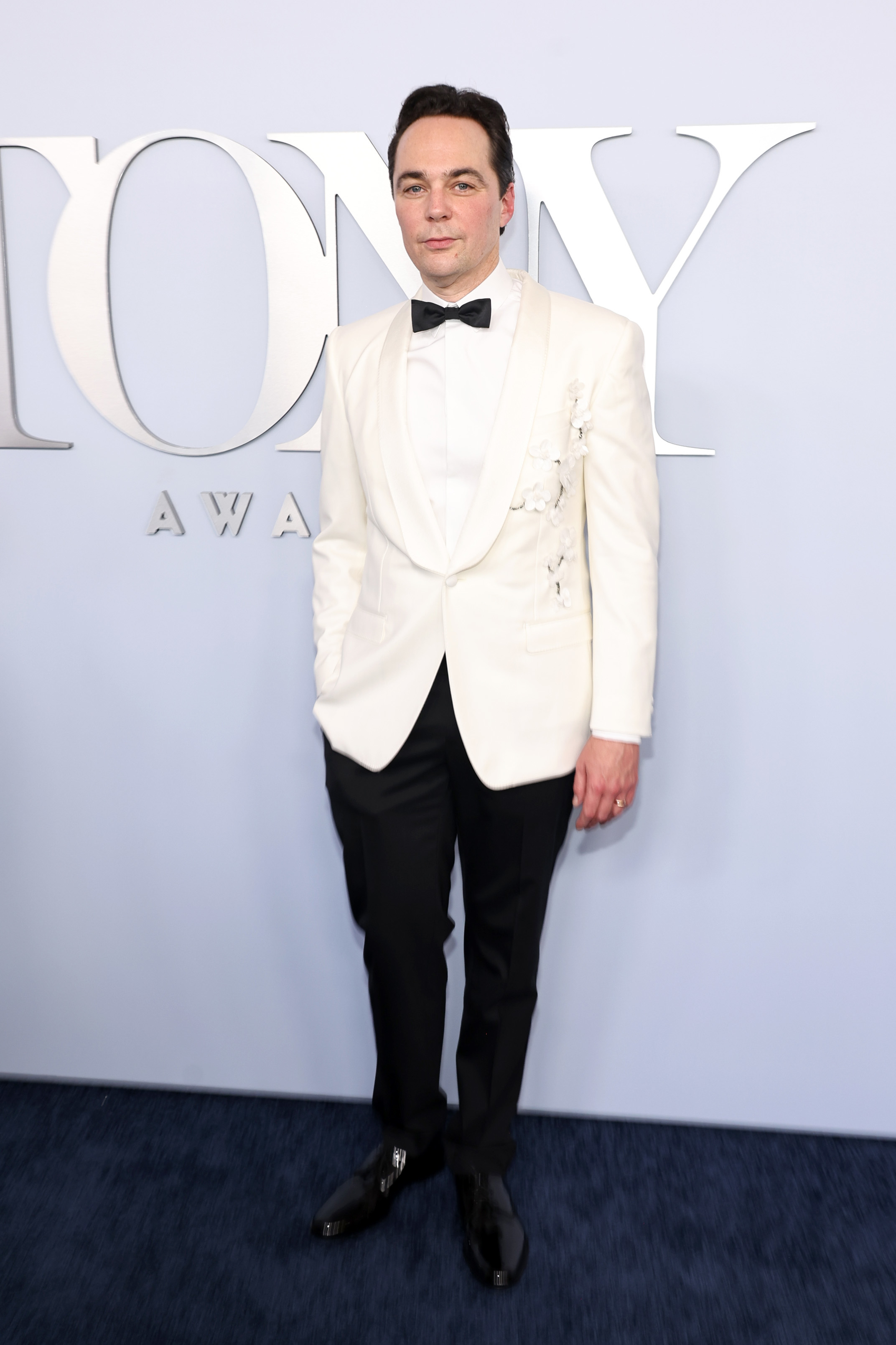 Jim Parsons stands in a tuxedo with a white jacket and black pants at the Tony Awards