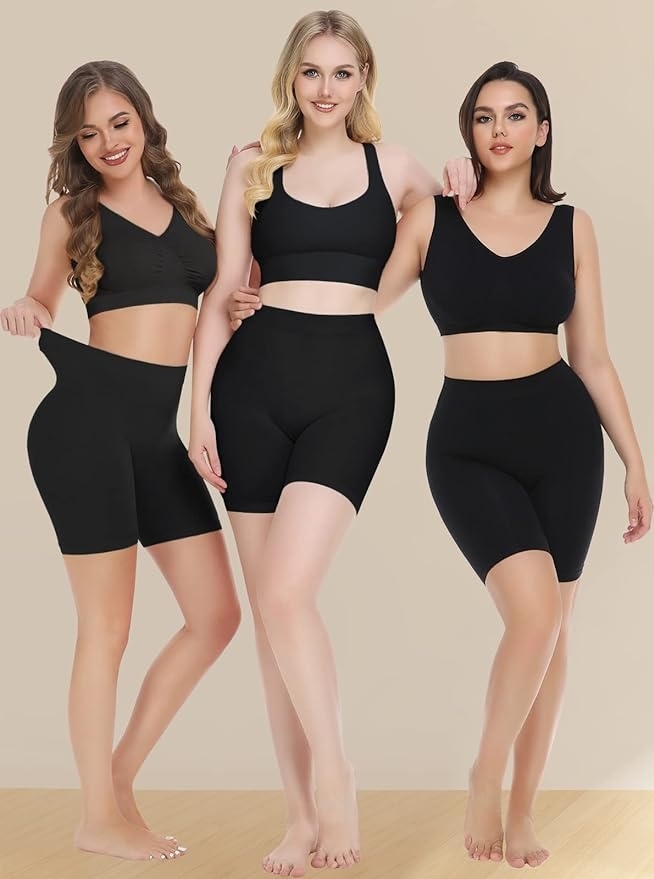 Three women smile while modeling  the black slip shorts with sports bras