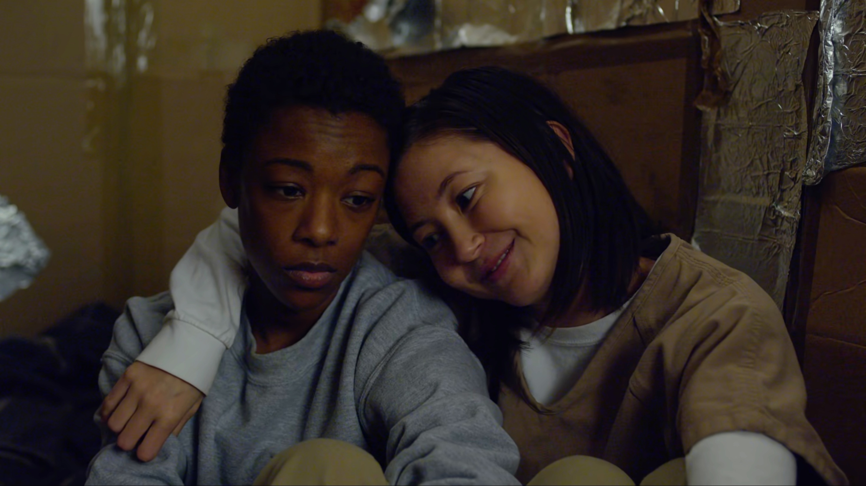 Brook sitting next to Poussey with an arm around her