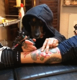 Persona con sudadera con capucha tatuando la pierna de otra persona en un estudio de tatuajes
