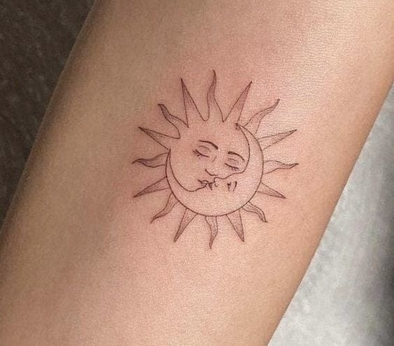 Tatuaje en el antebrazo que representa un diseño delicado del sol y la luna fusionados, con semblante tranquilo y detallado