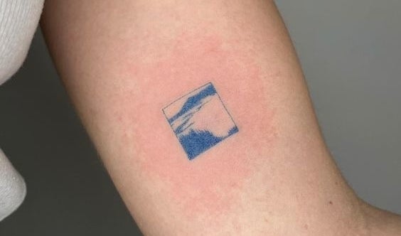 Brazo de una persona con un pequeño tatuaje cuadrado que representa un paisaje abstracto
