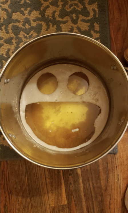A large pot with liquid inside shows a smiling face pattern formed by foam or residue floating on top