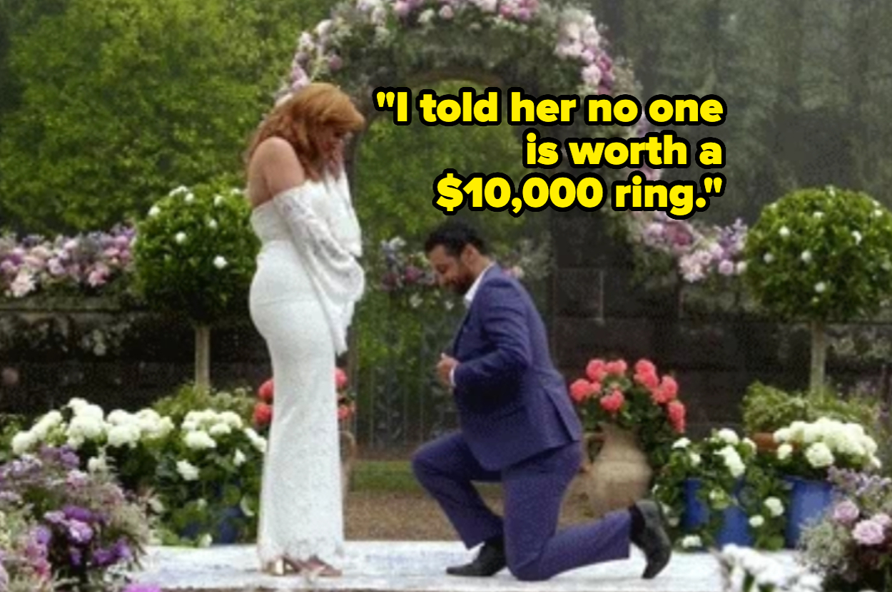 A man in a blue suit kneels and proposes to a woman in a white dress on an outdoor wedding setup with flower arrangements. Text: "I told her no one is worth a $10,000 ring."